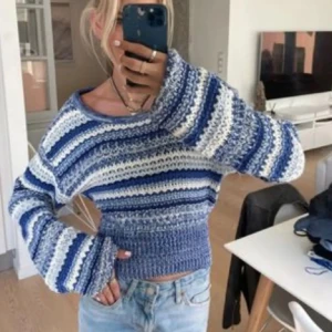 Blå och vit randig stickad tröja - Säljer en superfin stickad tröja i blått och vitt med randigt mönster. Den är croppad och har långa ärmar, perfekt för en avslappnad stil. Tröjan är i bra skick och passar perfekt till jeans för en casual look.