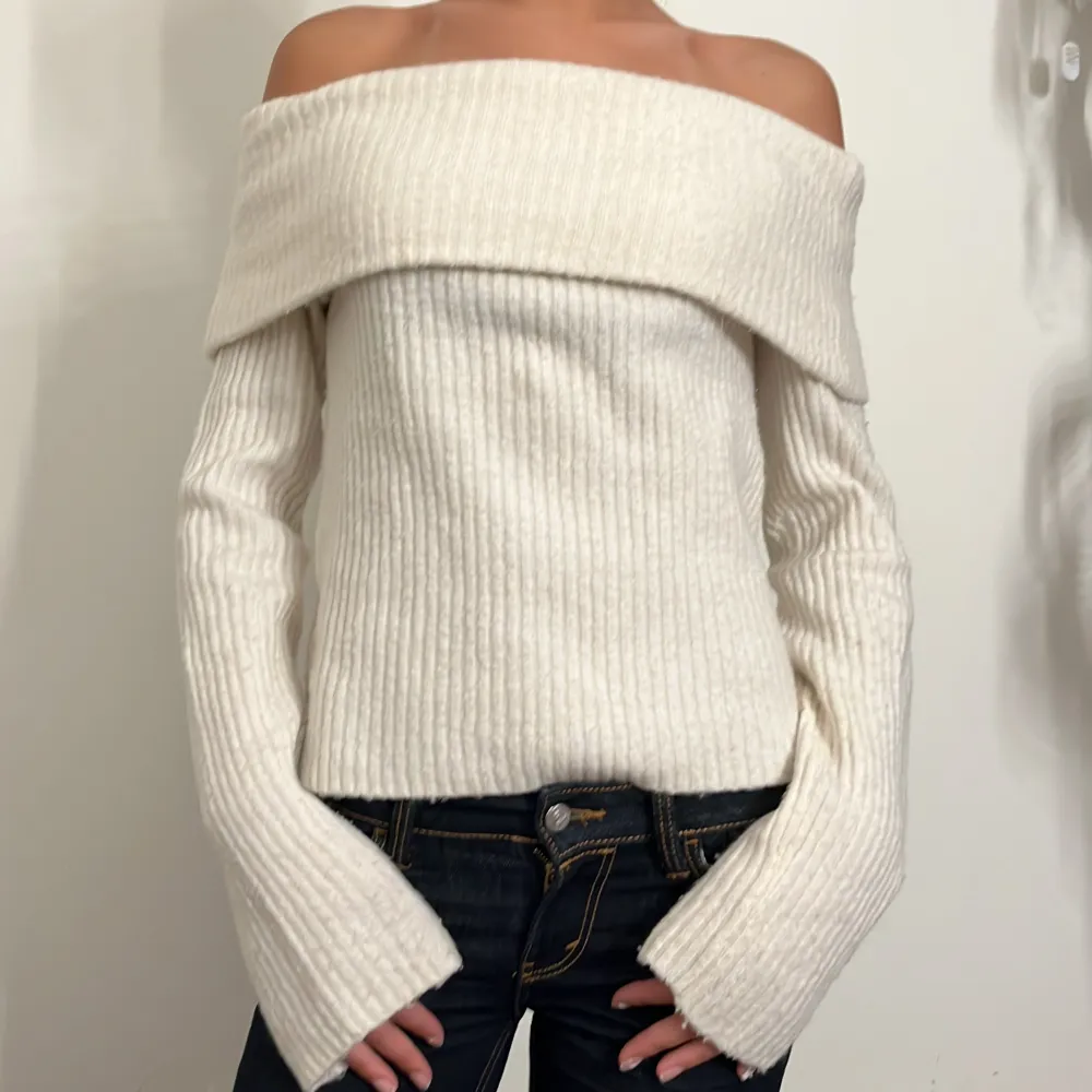 Säljer en superfin vit offshoulder tröja i ribbat material. Den har långa ärmar och en snygg, bred krage som ger en elegant look. Perfekt för både höst och vår när du vill ha något stilrent och bekvämt. Passar bra till jeans eller kjol för en chic outfit!. Tröjor & Koftor.