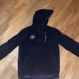 Svart jacka från Sail Racing - (S/M) Säljer en svart jacka från Sail Racing i mycket bra skick. Den har en huva och dragkedja framtill, perfekt för höst och vinter. Jackan har en cool logga på bröstet och en praktisk bröstficka med dragkedja. Perfekt för dig som gillar stil och funktion!