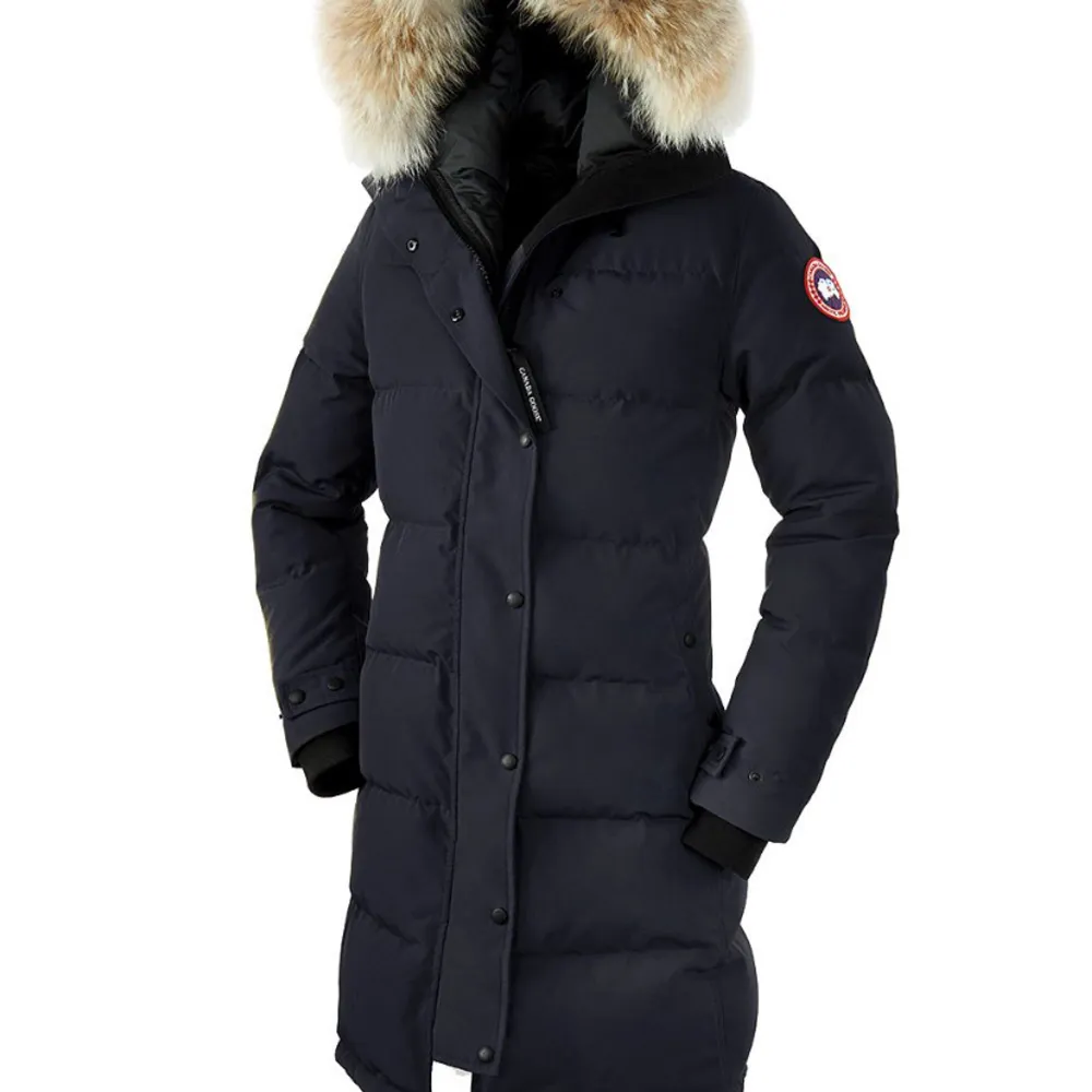 Säljer en svart dunjacka från Canada Goose med en lyxig pälsdetalj på huvan. Jackan är perfekt för kalla vinterdagar och har en lång passform med dragkedja och knappar. Den är i nyskick  och redo för nya äventyr. Tags och allt finns kvar . Perfekt för vinterns alla utmaningar! ❄️. Jackor.