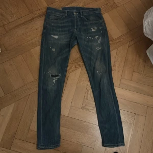 Blå jeans från Dondup - Säljer ett par snygga blå jeans från Dondup i bra skick. De har en cool slitningseffekt och en klassisk femficksdesign. Perfekta för en avslappnad stil eller en utekväll. Passar till det mesta och är superbekväma!