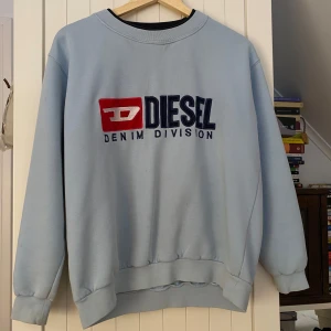 Ljusblå sweatshirt från Diesel - Säljer en supercool, ljusblå sweatshirt från Diesel med  tryck på framsidan.  Den är i använt skick, små fläckar kan förekomma men jag tror det mesta går bort i tvätten ☺️ tveka inte att höra av dig om du har några frågor! 