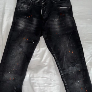Dsquared2 jeans strl S - Ett par riktigt feta dsquared2 jeans i svart med orange/vit färgstänkning. Varan är i nyskick. Strl S Inte äkta!!