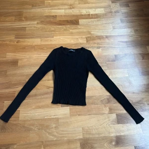 Svart stickad tröja  - Svart stickad ribbad tröja med tajt passform. Storlek är xs och aldrig använd. Säljer pågrund av att jag aldrig använder den. Fint skick då den är ny och inte använd. Inte lång utan går strax över naveln.