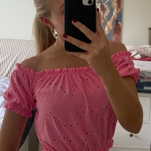 Rosa topp - Söt rosa topp med ”spets”-tyg. Går att använde både som off shoulder och på axlarna. Är av kortare modell så slutar över naveln.