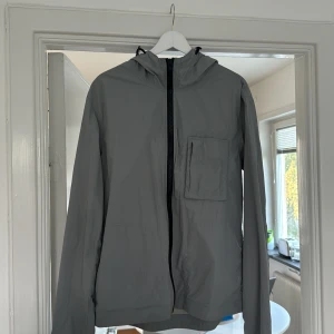 Peak Performance vindjacka - Peak Performance vindjacka i storlek L med en matte finish. Färg Concrete. Nypris 2000kr. Inköpt i Peak Performance butik i Stockholm.  Knappt använd och därför i mycket fint skick. Inget slitage.