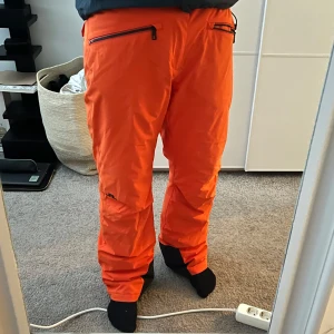 Orange skidbyxor från J.Lindeberg - Köpte dessa jättefina skidbyxor från j lindeberg förra julen. Endast använda en vecka i Åre förra året och fungerade galant där uppe i kylan. Byxorna är fordrade och alltså inte skalbyxor och är i toppskick. Något tecken på användning här o där såklart men fortfarande 8.5 skick av 10.   Nypris på dessa cirka 3000 därav mitt pris. Hör gärna dig vid frågor och funderingar! Plockas på Östermalm 