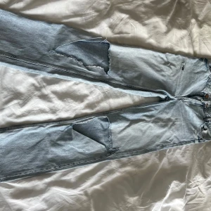 Ljusa jeans med slitningar från Bershka - Snygga ljusa jeans från Bershka med hög midja och slitningar på benen. Perfekta för en avslappnad stil. Jeansen har en straight passform och är tillverkade i denim.