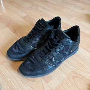 Philippe model skor  - Säljer dessa Philippe model skorna. De är helsvarta med ett mönster på sidorna och där fram. Skorna är i storlek 45 men små i storleken så skulle säga passar 44. 