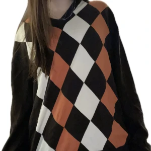 V-ringad brun tröja med harlekinmönster - Snygg och mysig brun tröja med ett harlekin/rutigt mönster i orange och vitt.