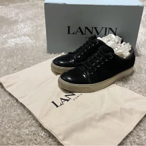 Svarta sneakers från Lanvin - Snygga svarta sneakers från Lanvin med en kombination av mocka och skinn. Skorna har en låg profil och klassisk snörning. Perfekta för en stilren look.