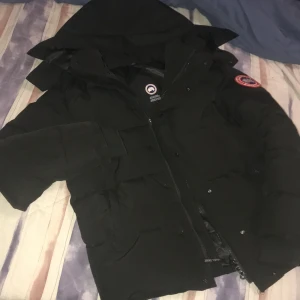 Canda goose - Säljer en svart Canada Goose wyndham parka med avtagbar huva, Jackan har dragkedja och knappar framtill för extra skydd mot kyla. Perfekt för kalla vinterdagar. Storlek s