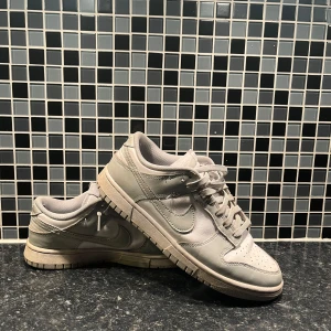 Grå Nike Dunk sneakers - Snygga grå Nike Dunk sneakers med klassisk design och snörning. Väl använda men fortfarande i bra skick!