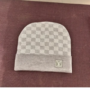 Grå rutig mössa/beanie  - Snygg grå mössa med ett klassiskt rutigt mönster. Mössan har en uppvikt kant med en broderad logga. Perfekt för att hålla stilen i kyligare väder. Pris kan diskuteras vid snabb affär