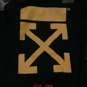 Svart hoodie från Off-White - Säljer en svart hoodie från Off-White med ikoniska gula pilar och texten 'CUT OFF'. Den har en stor grafisk tryck på framsidan och gula diagonala ränder på ärmarna. Perfekt för streetwear-entusiaster! storlek m men den funkar även xs - s!