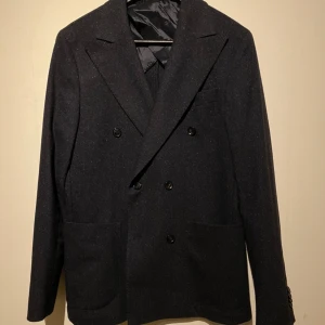 dubbelknäppt kavaj från Oscar Jacobsson - Elegant svart kavaj från Oscar Jacobson med dubbelknäppning och breda slag. Kontakta gärna för fler frågor. Nypris 5300, storlek:M , ALDRIG ANVÄND