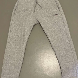 Grå mjukisbyxor från McKenzie - Snygga grå mjukisbyxor från McKenzie med dragsko i midjan och ribbade muddar vid bensluten. Perfekta för en avslappnad stil. Tillverkade i mjukt material för extra komfort.