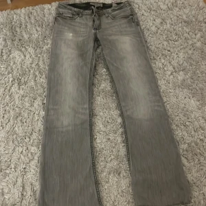 Grå jeans med coola designs - Lågmidjade bootcut jeans från J& company . Liten fläck på främre benet och en litet hål bak. Byxorna är avklippta så kom privat pm innerbenslängd . 