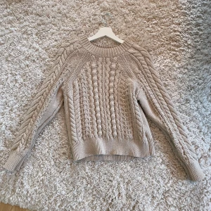 stickad tröja från COS - Säljer en snygg beige stickad tröja från COS med flätstickat mönster. 