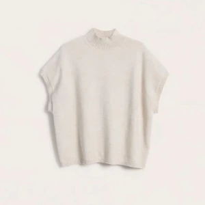 Beige stickad tröja - Säljer en stilren beige stickad tröja med korta ärmar och hög krage. Tröjan har en ribbad krage och är tillverkad i ett mjukt material.