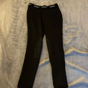 Svarta fodrade rid tajts med fäste - Snygga svarta rid tajts från CRW med elastisk midja. Perfekta för höst uteritter.