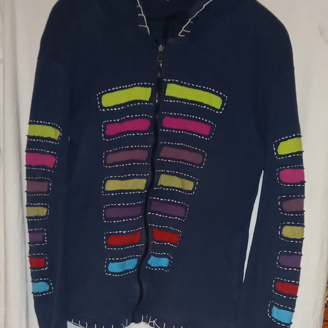 Mörkblå jacka med färgglada detaljer och med annorlunda huva