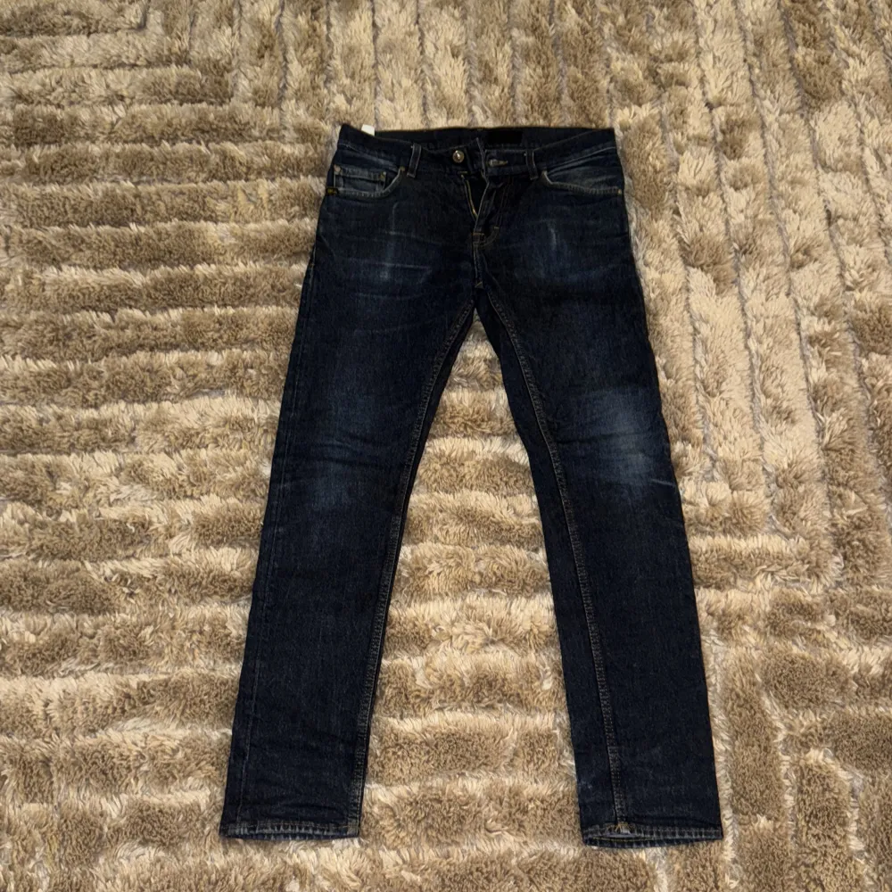 Snygga mörkblå jeans från Tiger of Sweden med klassisk femficksdesign och dragkedja. Perfekta för en stilren look. Märkesdetalj i läder baktill. Jeansen har använts måttligt och det finns tecken på användning, absolut inga defekter däremot!. Farkut & Housut.