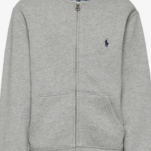 Grå hoodie från Ralph Lauren - Säljer en stilren grå hoodie från Ralph Lauren med dragkedja. Den är i storlek XL i barn storlek som motsvarar ca XS/S i herr storlek. Tröjan är väl använd men har fortfarande mycket kvar ge. Den har inga större defekter för utom en liten svart fläck vid armhålan som man dock inte tänker på när man har på sig tröjan. Även att tröjan sitter lite löst längst ner. Vid frågor eller funderingar är det bara att höra av sig!🤩 