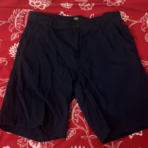 Mörkblå shorts från 157 - Snygga mörkblå shorts från 157 med knapp och dragkedja framtill. Perfekta för en avslappnad stil. De har fickor både fram och bak, vilket gör dem praktiska för vardagsbruk.