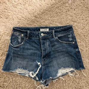 Blå jeansshorts från Pimkie - Snygga blå jeansshorts från Pimkie med fransiga kanter och klassisk femficksdesign. Perfekta för en avslappnad stil.