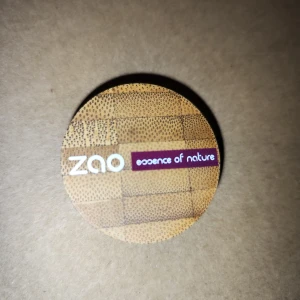 Ögonskugga från Zao - Säljer en naturlig ögonskugga från Zao i en snygg bambuförpackning. Färgen är en skimrande brun nyans som passar perfekt för både vardag och fest. Förpackningen är hållbar och miljövänlig, vilket gör den till ett bra val för den miljömedvetna. Perfekt för att skapa en naturlig look med lite extra glans!