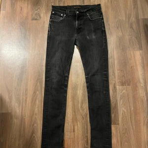Nudie Jeans - Säljer ett par superfeta mörkgråa Nudie Jeans i strlk W30 L34🎶 Liten slitning som kan ses på sista bilden, men nudie lagar sådant gratis!♻️ HMU om du har några frågor🏠
