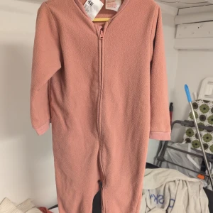Rosa fleeceoverall från H&M - Mysig rosa fleeceoverall från H&M i storlek 92. Fint begagnat skick(Inte Nyskick!), mörkare än nytt, Trasigt vid dragkedjan, men det påverkar inte funktionen. Vänligen se bilder. Jag postar inom tre dagar efter köp (varje torsdag och söndag).