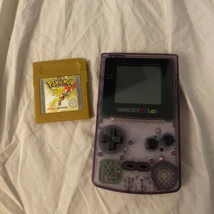 Game Boy Color med Pokémon-spel - Säljer en genomskinlig lila Game Boy Color från Nintendo tillsammans med Pokémon Yellow Version. Konsolen är i bra skick och fungerar perfekt. Batteriluckan är intakt och det finns två Panasonic-batterier i den. Perfekt för nostalgiska spelstunder! 🎮