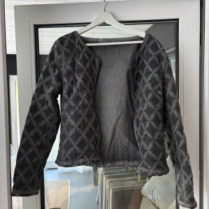 Grå quiltad jacka från Moon Row - Säljer en snygg grå/svart jacka från Moon Row. Den har ett coolt mönster och är perfekt för höst och vår. Jackan är långärmad och har en normal passform. Blixtlås finns. Perfekt för att hålla sig varm och stilren!