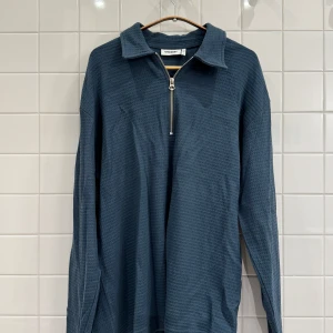 Mörkblå tröja med dragkedja från Weekday - Säljer en snygg mörkblå tröja från Weekday. Den har en cool dragkedja framtill och är gjord i ett bekvämt material med struktur. Perfekt för både vardag och lite mer avslappnade tillfällen. Passar bra till jeans eller chinos!