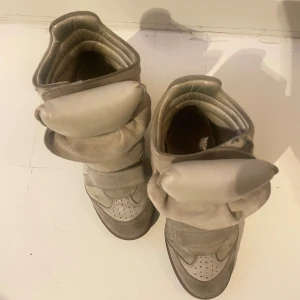 Isabel marant sneakers  - Ett par beigea skor från Isabel Marant, i sneakers med kilklack, måttligt använda kan behövas en upp-putsning. Säljer pga att jag inte använder dem så ofta längre, annars väldigt fina skor. 🧡 Storlek 36, jag har 35 o det funkade också. 