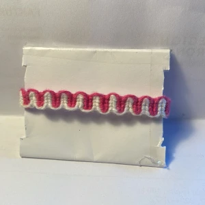  Armband -  Handgjort armband i bomullsgarn, Man kan ändra storleken 13-22, 1 cm brett. Armbandet är mörk rosa och vitt.