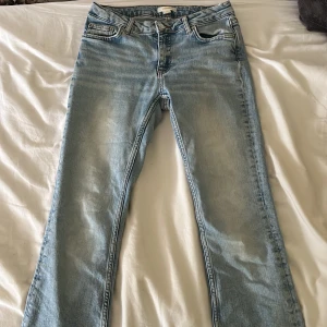 Ljusblå jeans från Gina Tricot - Säljer ett par ljusblå jeans från Gina Tricot. De är i en straight fit och har en hög midja. Jeansen har en klassisk femficksdesign och en dragkedja med knapp framtill. De är i bra skick och har en snygg slitning vid bensluten.