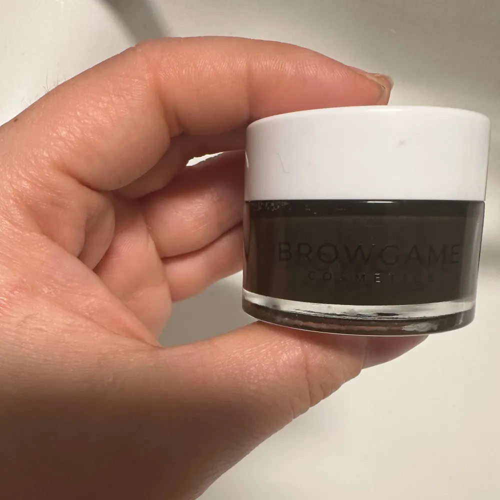 Säljer en Browgame Cosmetics Instant Brow Lift Wax. Den kommer i en liten rund burk med vit lock och genomskinlig botten. Perfekt för att forma och lyfta dina ögonbryn för en snygg och hållbar look. Produkten är lätt att applicera och ger ett naturligt resultat. använd en gång men färgen passade ej mig. . Skönhet.