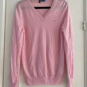 Rosa v-ringad tunn stickad tröja från J.Lindeberg i strl M - Rosa v-ringad tunn stickad tröja från J.Lindeberg i strl M.  Sparsamt använd men tyvärr är där lite fläckar under armhålorna, i övrigt i bra begagnat skick.  Mått Över bröstet: ca 49 cm Längd från axeln och ner: ca 68 cm  100% merinoull 