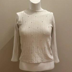 En tröja med vita pärlor - En vit, lite tjockare tröja med vita pärlor på hela framsidan. Bra skick 