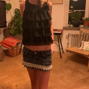 Jeanskjol med spetsdetaljer - Säljer en superfin jeanskjol med spetsdetaljer längst ner. Kjolen är kort och har en tight passform. Den har två fickor bak och två små dragkedjor fram som detaljer. Perfekt för sommarens alla fester! 🥳