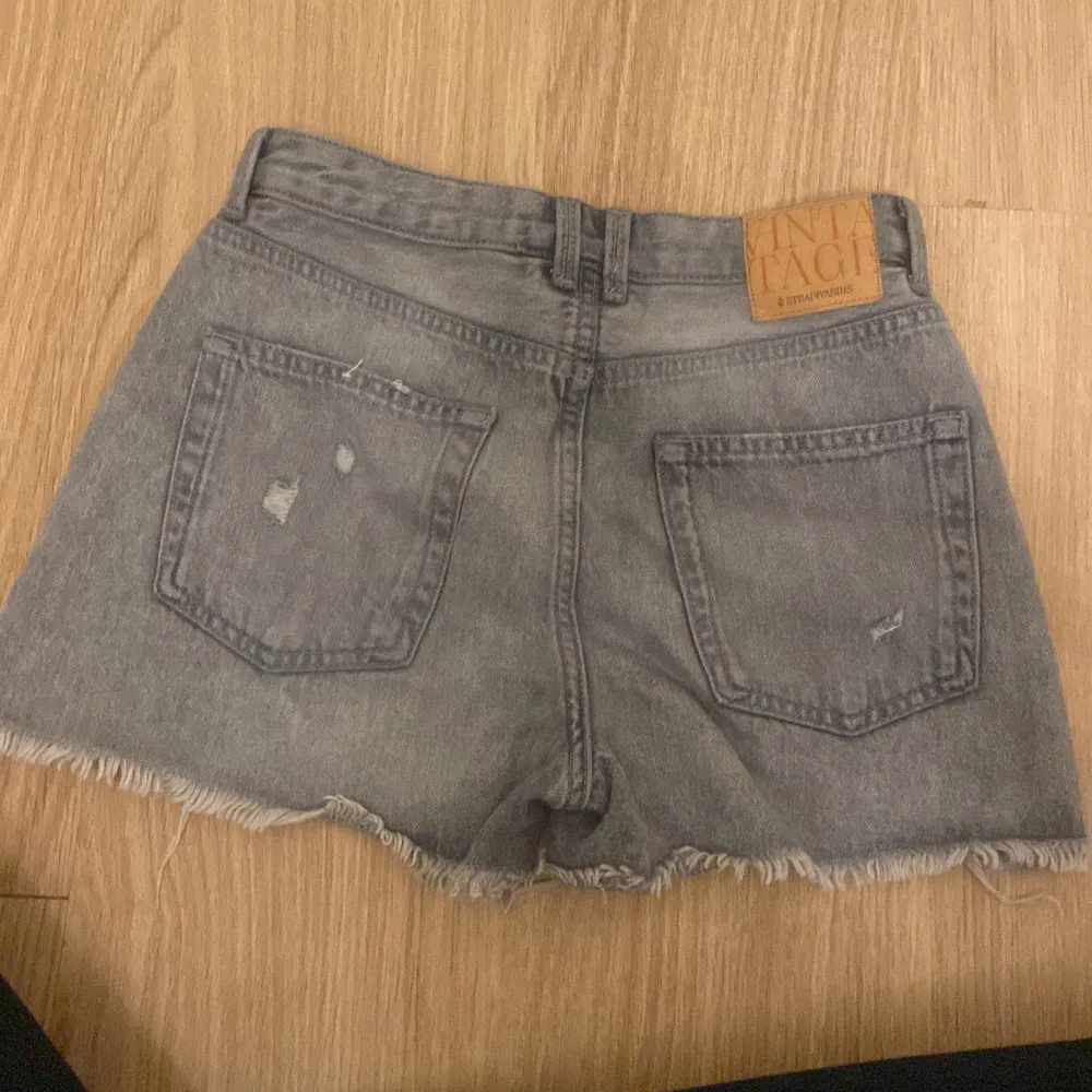 Säljer ett par grå jeansshorts från Stradivarius i storlek 36. De är i en vintage-stil med slitna detaljer och fransig kant. Perfekta för sommaren! 🩳. Shorts.