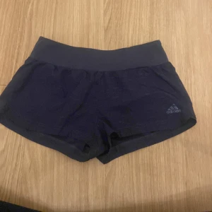 Svarta träningsshorts från Adidas - Säljer ett par marinblå träningsshorts från Adidas. De är i nyskick och har en tight passform. Perfekta för träning eller löpning. Shortsen har en bred elastisk midja för extra komfort.