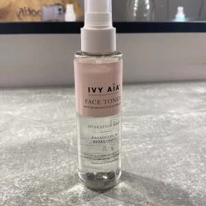 Face Toner från Ivy Aïa - Säljer en face toner från Ivy Aïa med hyaluronsyra och niacinamid. Denna toner är perfekt för att balansera och fräscha upp huden. Den kommer i en genomskinlig plastflaska med en rosa etikett och vit spraypump. Flaskan innehåller 120 ml och är tillverkad av 100% återvunnen plast.