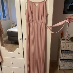 Rosa finklänning  - Rosa finklänning i bra skick som behöver sys på ett ställe om man vill ha den tråden kvar annars går det att klippa bort den tråden för den är bara till bandet som ska vara knyten runt midjan, se bild 3. Köpt på new yorker och använd en gång. 