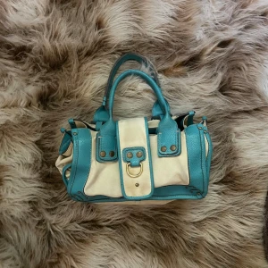 Väska  -  En blå och vit väska med guldaccessoarer 