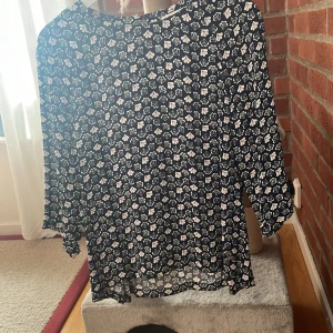 Blommig blus från Dobber - Säljer en söt blommig blus från Dobber i storlek 36. Blusen är mörk blå med ett vitt och rosa blommönster. Den har trekvartsärmar och är perfekt för både vardag och fest. Materialet känns lätt och luftigt, vilket gör den bekväm att bära hela dagen.