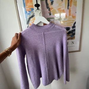 Ljuslila stickad tröja - Säljer en superfin ljuslila stickad tröja. Den är riktigt mjuk och skön, perfekt för kyliga dagar. Tröjan har en hög krage och långa ärmar. Den är i nyskick och passar perfekt till höst och vinter. 💜